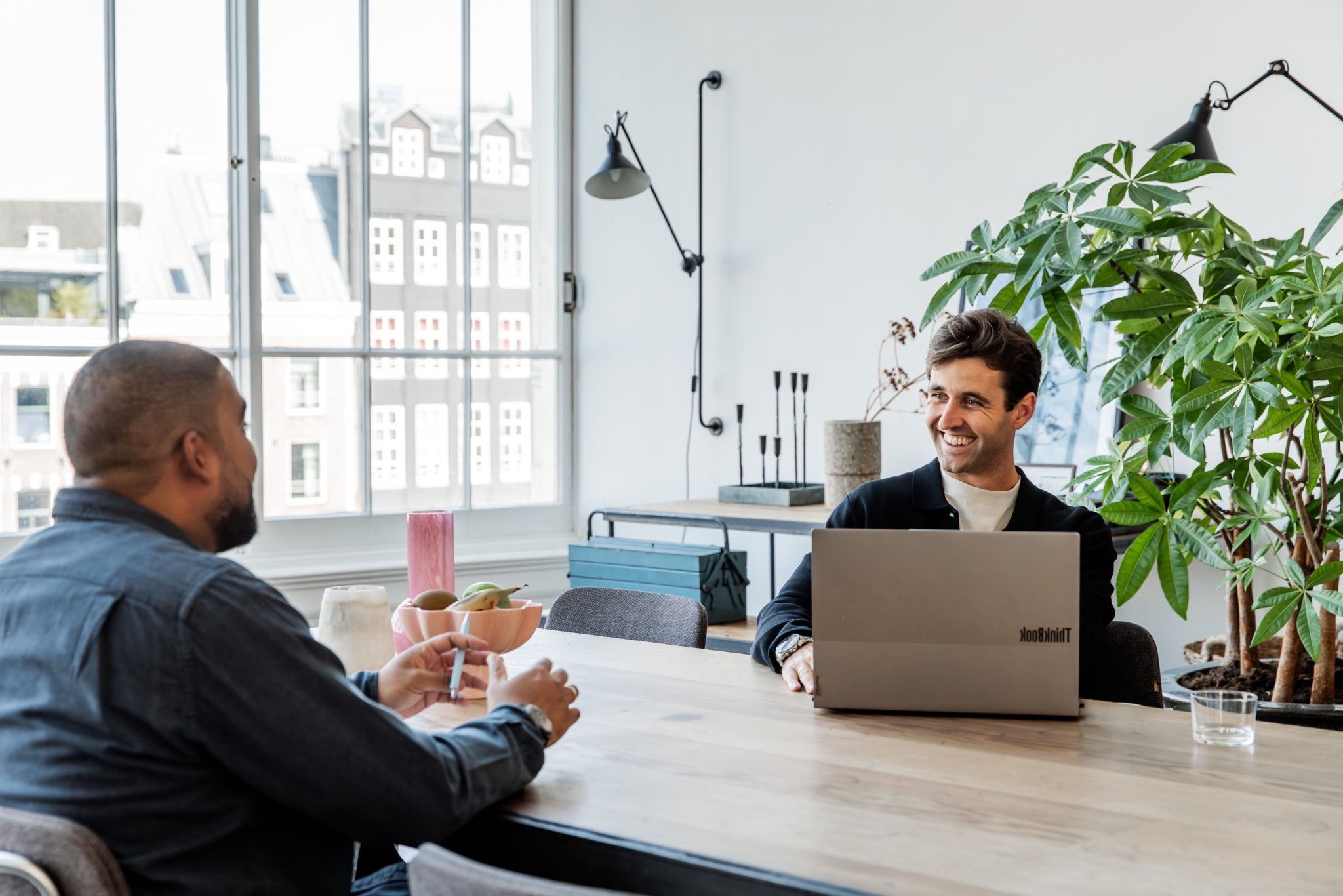 Ondernemer lacht achter zijn laptop tijdens een gesprek bij Consult&Co.