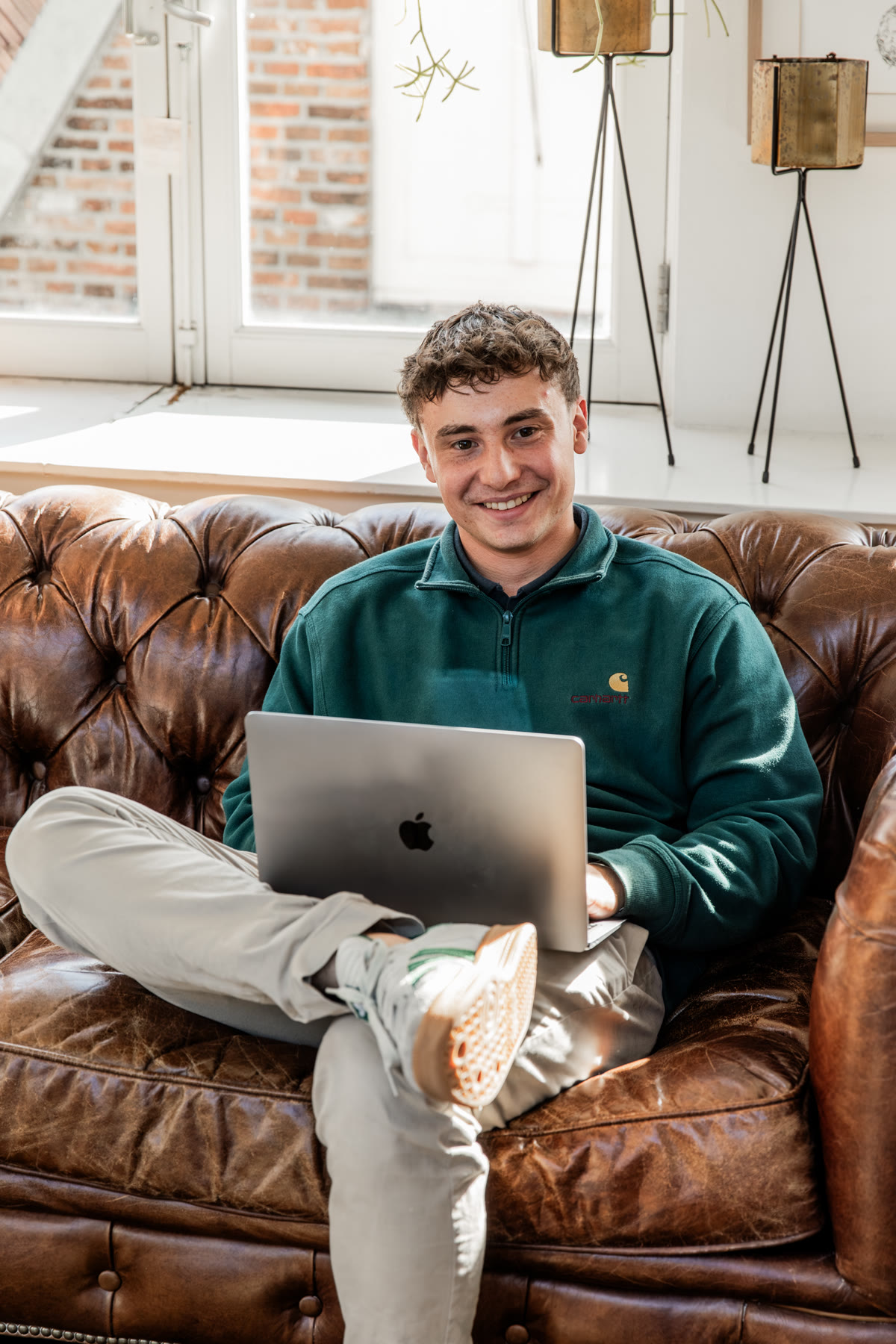 Ondernemer werkt ontspannen op zijn laptop in een leren bank